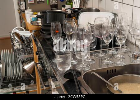 Cuisine après un dîner plus grand, partie de cuisine, lave-vaisselle, plein, avec vaisselle nettoyée, verres sales, casseroles, ustensiles de cuisine sur l'évier, en attente d'être Banque D'Images