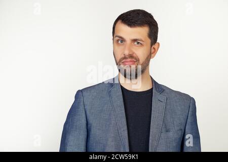 Jeune homme d'affaires avec une barbe dans une veste, sceptique et nerveux, frognant, bouleversé à cause du problème. Personne négative. Portrait d'un homme sur fond gris. Banque D'Images