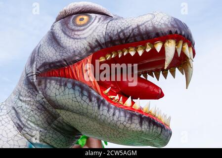 Tête de dinosaure gonflable sur une aire de jeux pour enfants contre l'arrière-plan du ciel Banque D'Images
