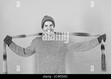 Réchauffer les froides journées d'écharpe. Homme heureux porter une écharpe. Beau gars sourire avec foulard en mains. Accessoire de mode pour l'hiver. Tricot chic foulard à rayures. Banque D'Images