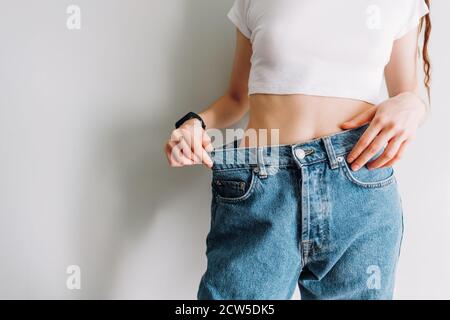 Femme tient le Jean à la main, montre une taille mince corps féminin dans le grand Jean Banque D'Images