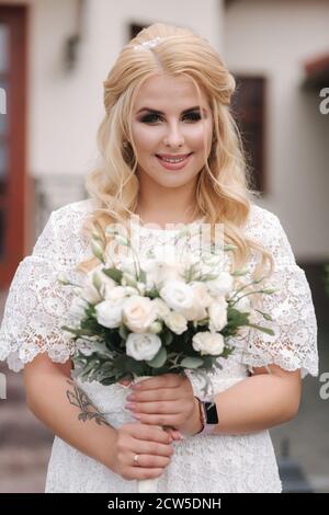 La femelle tient un bouquet de roses blanches dans les mains. Mini mariage. Mariée de cheveux blonds avec bouquet de fleurs Banque D'Images