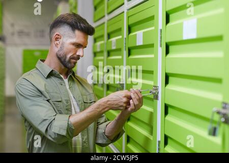 Taille vers le haut portrait de beau barbu homme ouverture cadenas sur la porte de l'unité de stockage libre-service , espace de copie Banque D'Images