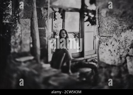 Fille assise dans une ancienne maison abandonnée Banque D'Images