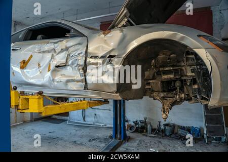 Voiture de sport cassée ou endommagée après un accident de la route ou une collision dans un atelier de réparation de garage, en gros plan Banque D'Images