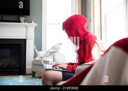 Vue de côté de Tween Boy en Sweatshirt à capuche travaillant sur ordinateur portable Banque D'Images