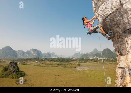 Femme grimpeur tirant sur le rocher suspendu à Yangshuo / Chine Banque D'Images