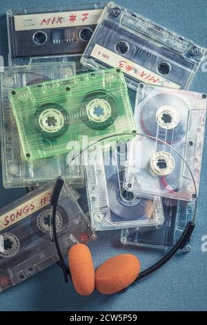 Pile de cassettes anciennes avec écouteurs orange sur fond bleu canapé Banque D'Images