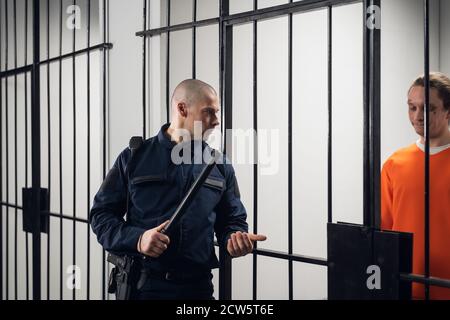 Un surveillant en uniforme dans une prison asiatique fait une visite en soirée des cellules avec des prisonniers. Banque D'Images