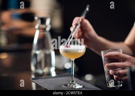 Gros plan d'un verre avec un délicieux cocktail sur la table dans un restaurant. Le barman crée une boisson alcoolisée pour les femmes. Banque D'Images