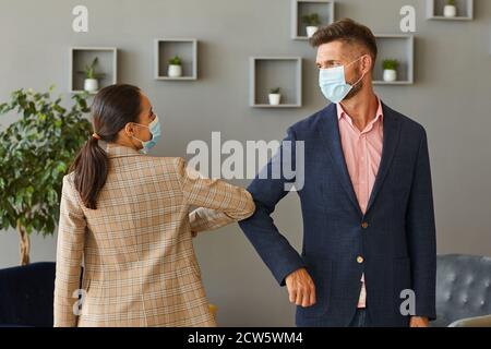 Portrait de deux hommes d'affaires qui ont réussi à porter un masque et des coudes qui se cognent comme salutation sans contact dans un bureau post-pandémie Banque D'Images