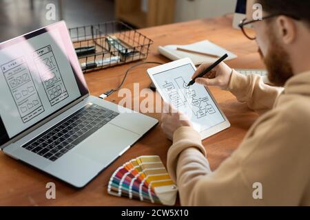Jeune développeur de logiciels freelance mâle tenant le stylet sur l'écran de la tablette Banque D'Images