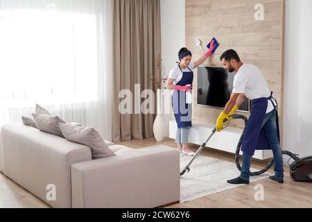 L'équipe de nettoyage professionnelle nettoie le salon de l'appartement moderne Banque D'Images