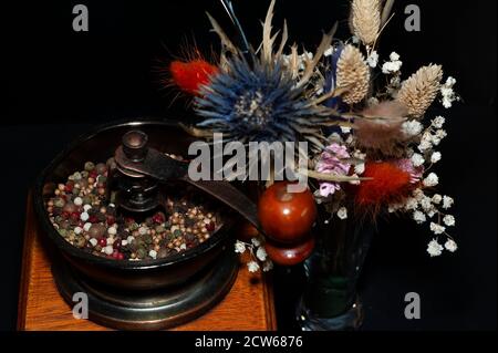 photo d'art d'un moulin à poivre et d'un bouquet de fleurs séchées gros plan sur fond noir Banque D'Images