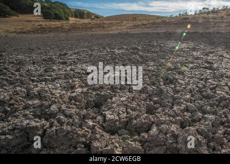 Un étang de bétail séché dans les collines de la baie est dans le nord de la Californie, les pluies sont devenues moins régulières et l'eau a séché en laissant seulement la boue durcie. Banque D'Images