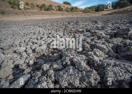 Un étang de bétail séché dans les collines de la baie est dans le nord de la Californie, les pluies sont devenues moins régulières et l'eau a séché en laissant seulement la boue durcie. Banque D'Images