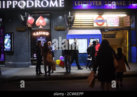 Les gens à l'extérieur de la station de métro Leicester Square à Londres, après l'entrée en vigueur d'une série de nouvelles restrictions pour lutter contre l'augmentation des cas de coronavirus en Angleterre. Banque D'Images