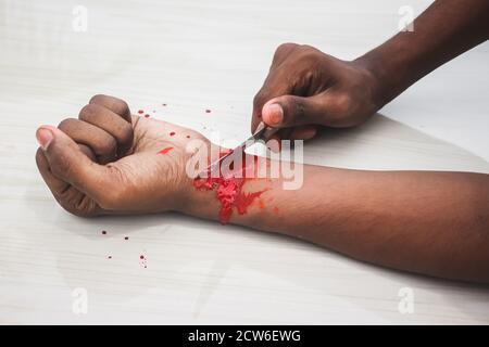 Concept de suicide engagé - l'homme suicide par couteau en coupant un poignet, l'homme déprimé, l'amour triste, faible estime de soi, la main de couteau et beaucoup de sang. À couper Banque D'Images