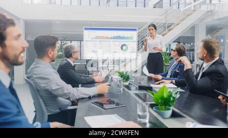 Dans la salle de réunion d'entreprise : l'analyste féminin utilise le tableau blanc interactif numérique pour la présentation à un conseil d'administration, à des avocats et à des investisseurs Banque D'Images
