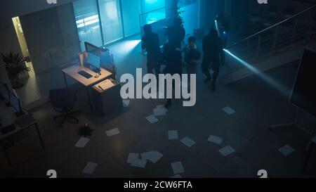 Une équipe masquée d'officiers de police SWAT armés sauve une prise d'otage femelle dans un immeuble de bureaux saisi à l'obscurité avec des bureaux et des ordinateurs. Soldats avec fusils et Banque D'Images