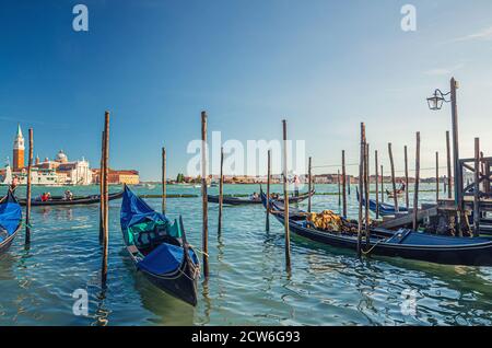 Gondoles amarrées sur l'eau dans la ville de Venise. Gondoles naviguant dans la voie navigable du bassin de San Marco. Île de San Giorgio Maggiore avec le Campanile de San Giorgio dans le lagon vénitien et l'île de Giudecca, Italie Banque D'Images