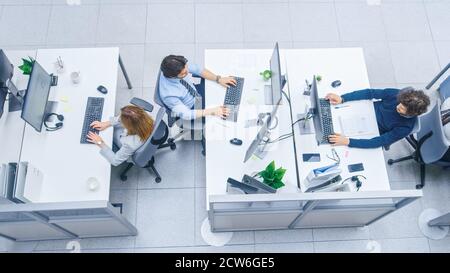 Dans les rangs de bureaux très occupés de divers professionnels travaillant sur des ordinateurs de bureau, parler, faire le support client, communiquer avec les clients Banque D'Images