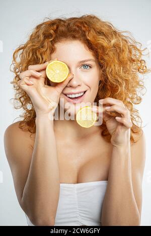Joyeux sourire rouge cheveux femme tenant des tranches de citron à la main Banque D'Images