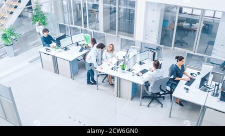 Dans Bright Office Rows de jeunes professionnels travaillant sur les ordinateurs de bureau, parler, faire le support client, communiquer avec les clients, surveillance Banque D'Images