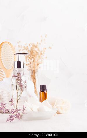 Produits cosmétiques faits maison et accessoires en bois naturel pour l'hygiène et le nettoyage de la peau, spa avec une élégante branche lavande dans un intérieur blanc clair et doux Banque D'Images