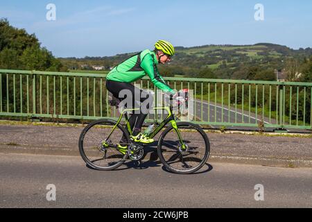 Cycliste mâle à cheval jaune noir Cannondale Synapse carbone 105 se sport route vélo sur la campagne route traversant le pont d'autoroute dans la campagne Lancashire, Royaume-Uni Banque D'Images