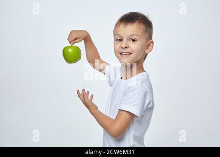 Mignon garçon tenant une pomme verte. Séance de photo dans le Studio sur un fond blanc Banque D'Images