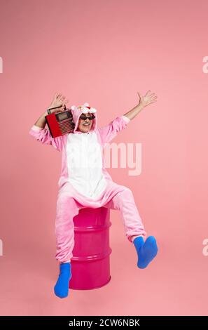 Écouter de la musique à l'aide d'un plateau tournant. Portrait de l'homme hipster senior dans une tenue élégante isolée sur fond rose studio. Concept de mode de vie technologique et joyeux pour les personnes âgées. Couleurs tendance, toujours jeune. CopySpace Banque D'Images