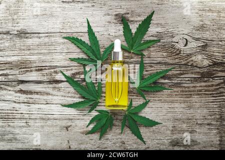 Sérum d'huile de chanvre cbd dans un flacon compte-gouttes en verre sur les feuilles de cannabis. Feuille de cannabis avec produit cosmétique pour le soin de la peau huile de CBD sur fond de bois ancien. Banque D'Images