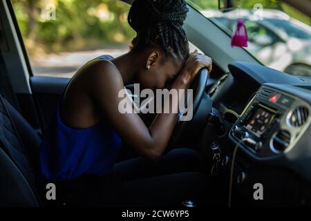 Femme fatiguée endormie sur le volant dans sa voiture Banque D'Images