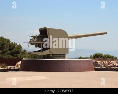 Vieux canon militaire au château de Montjuïc à Barcelone Espagne pointant vers la droite. Ciel bleu clair avec ville en arrière-plan. Banque D'Images