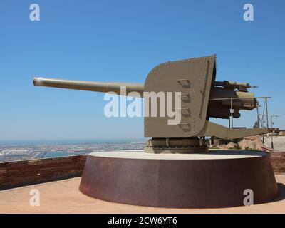 Vieux canon militaire au château de Montjuïc à Barcelone Espagne pointant vers la gauche. Ciel bleu clair avec ville en arrière-plan. Banque D'Images