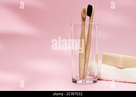 Brosses à dents en bambou en verre et ombres à feuilles sur fond rose Banque D'Images