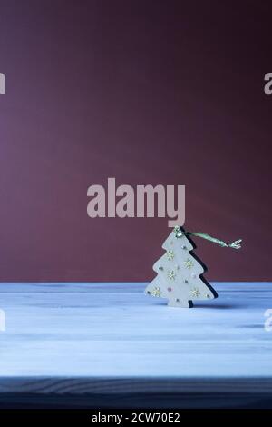 Jouet de Noël sous la forme d'un arbre de Noël en bois, debout sur une table bleue sur fond violet. Banque D'Images