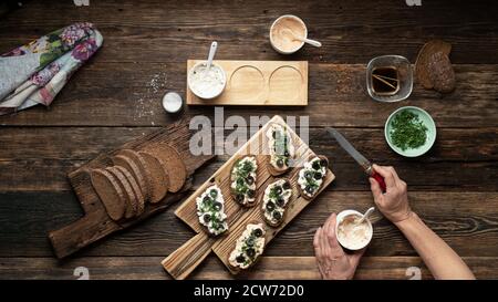 Femme préparant des sandwiches végétaliens sur une table en bois, vue de dessus Banque D'Images