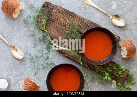 Soupe de tomates dans un bol noir sur fond de pierre grise. Copier l'espace.vue de dessus. Banque D'Images