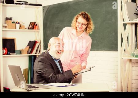 Vérifier les devoirs. Éducateur et étudiant regardant le livre. Expliquer un sujet difficile. L'étudiant est perplexe par quelques informations. Un étudiant demande à l'enseignant la tâche. Résolution des tâches mathématiques. Concept d'éducation scolaire. Banque D'Images