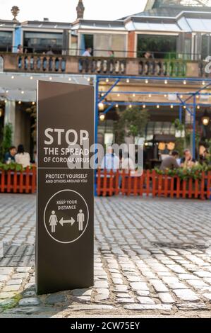 LONDRES - 12 SEPTEMBRE 2020 : panneau d'avertissement Covid 19 social de distanciation à Covent Garden avec des dîneurs dans un restaurant en plein air en arrière-plan Banque D'Images