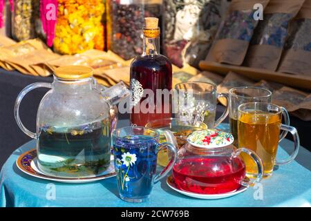 Théière en verre et tasses avec différentes sortes de tisanes sur la table dans un marché de rue Banque D'Images