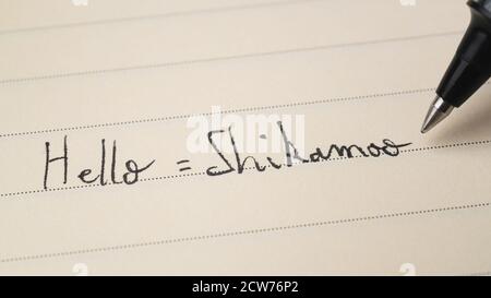 Débutant Swahili langue apprenant à écrire Bonjour le mot formel Shikamoo pour devoirs sur une macro de bloc-notes Banque D'Images