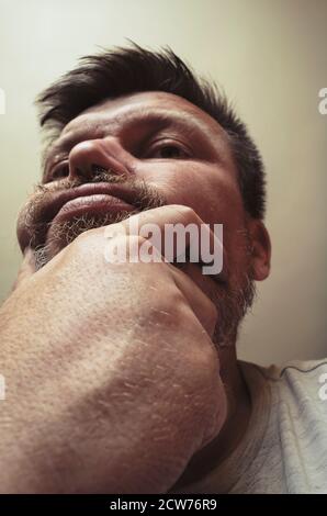 Portrait inhabituel d'un homme barbu adulte. Un homme de 44 ans avec une barbe grimace devant l'appareil photo. Gros plan. Mise au point sélective. Banque D'Images