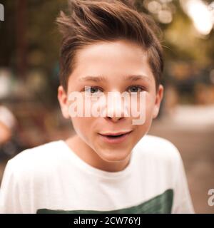 Beau blond drôle adolescent garçon de 14-16 ans avec la coiffure élégante posant à l'extérieur gros plan. Regarder l'appareil photo. Teenagerhood. Banque D'Images