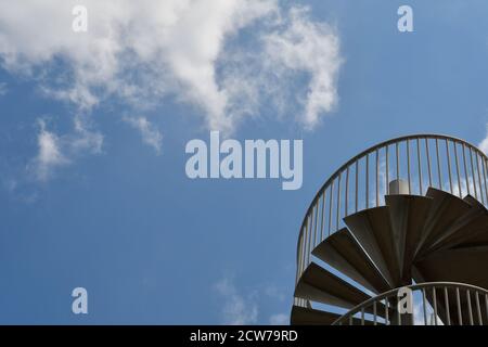 Un ciel bleu abstrait avec des nuages blancs et un escalier métallique en spirale dans le coin. Banque D'Images