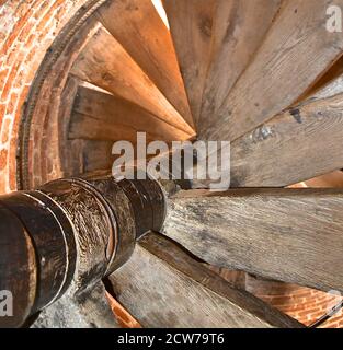 Vue sur un vieux escalier en colimaçon en bois dans une tourelle circulaire en brique dans une ancienne tour d'église médiévale en brique. Banque D'Images