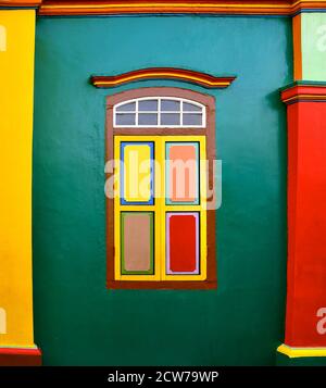 Volets en bois colorés sur un bâtiment restauré avec des murs vert vif et des colonnes jaunes et rouges. Banque D'Images