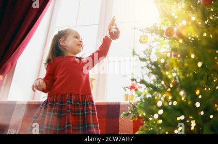 Joyeux Noël et joyeuses fêtes ! Joli petit enfant avec des boules près de l'arbre à la maison. Banque D'Images